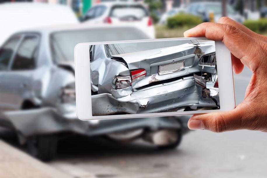 a person taking pictures of the damage to their car after an accident.